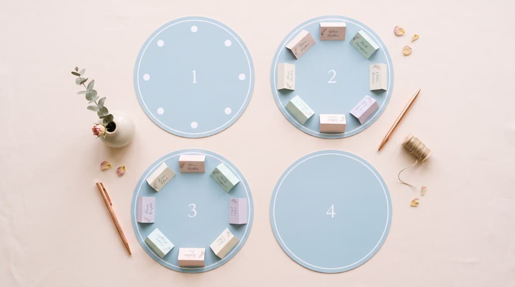 Plan de table mariage en préparation : tables numérotées et marque-places pastel disposés sur un bureau